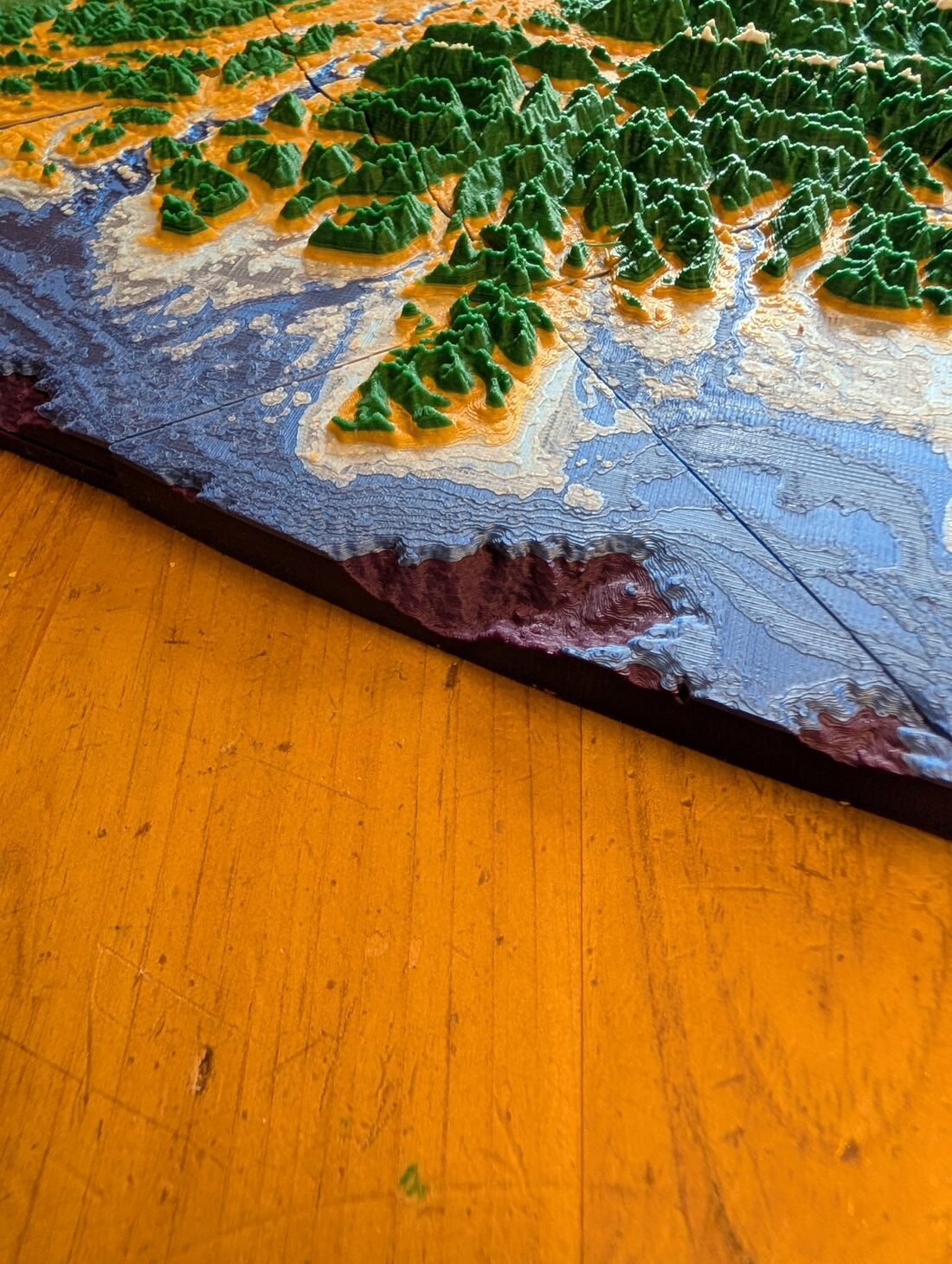 Close-up of the printed map's outer edge on the west coast, where the model tapers to a thin dark rim only a few millimetres thick.